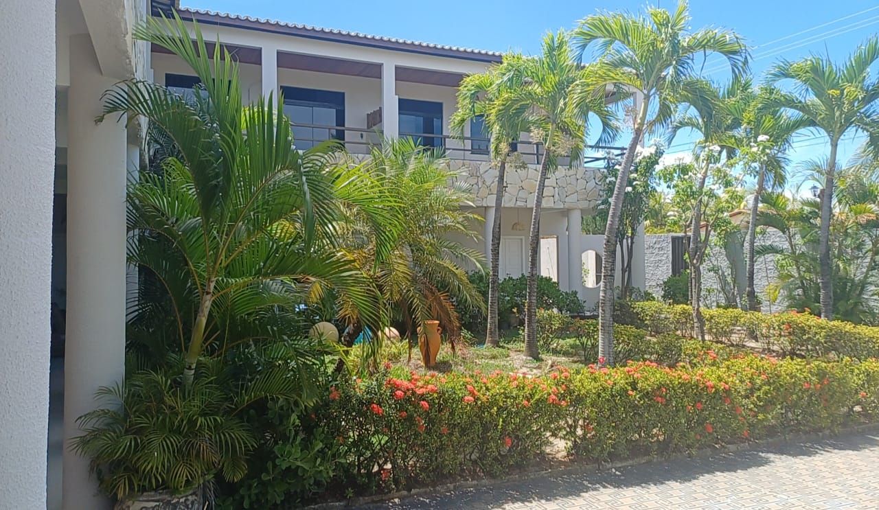 A building with a stone facade, surrounded by lush greenery and palm trees.