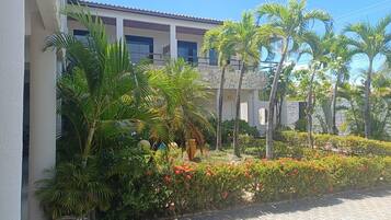 A building with a stone facade, surrounded by lush greenery and palm trees.