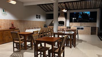 An outdoor dining area with brick walls, wooden tables and chairs, and hanging lights.