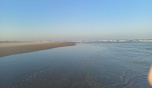 Una playa con una amplia orilla arenosa y olas suaves.