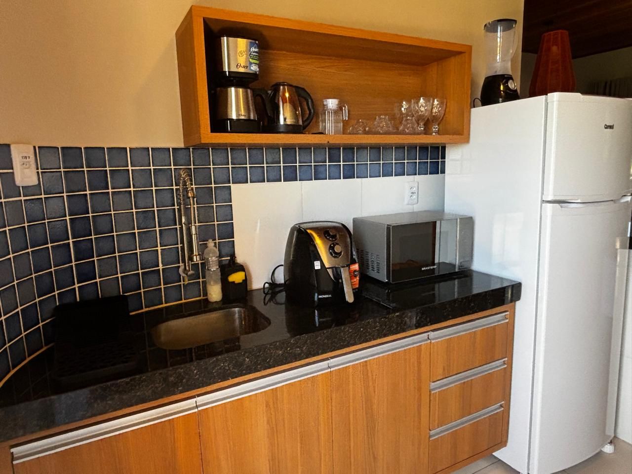 A compact kitchen with a sink, a toaster, a microwave, and a refrigerator.