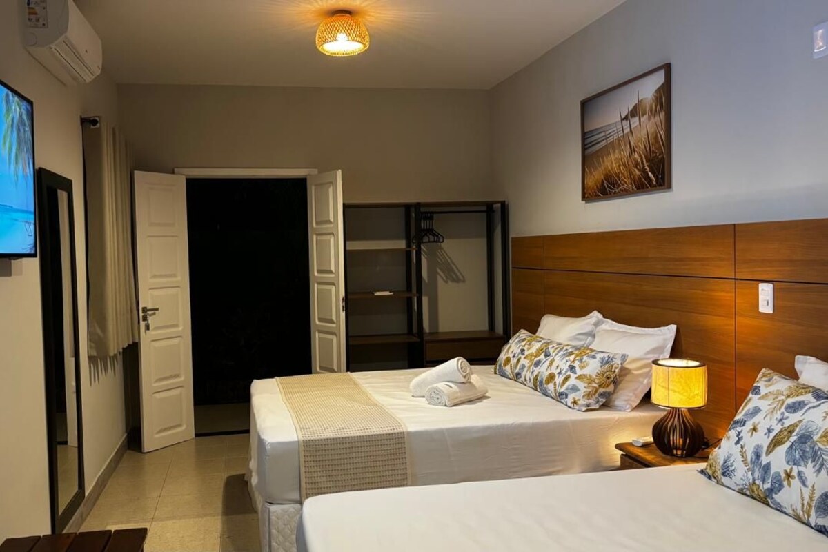 Habitación de hotel con cama, televisión, puerta y un cuadro en la pared.