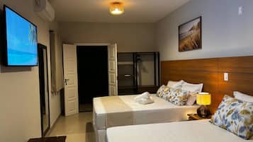 A hotel room with a bed, a TV, a door, and a wall-mounted picture.