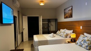 Habitación de hotel con cama, televisión, puerta y un cuadro en la pared.