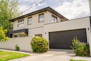 A modern two-story house with a garage, a small front yard, and a variety of shrubs. - Luxury 4 Bedroom House - Sauna, 3 En-suites (Bentleigh East)