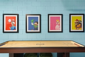 A room with a foosball table and four framed pictures on the wall. - South Pool | Arcade Game Room | Near Disney 9039 (Kissimmee)