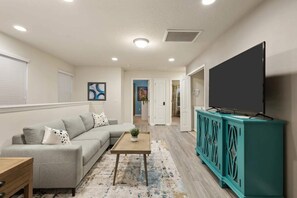 A living room with a sofa, coffee table, and a television on a cabinet. - South Pool | Arcade Game Room | Near Disney 9039 (Kissimmee)