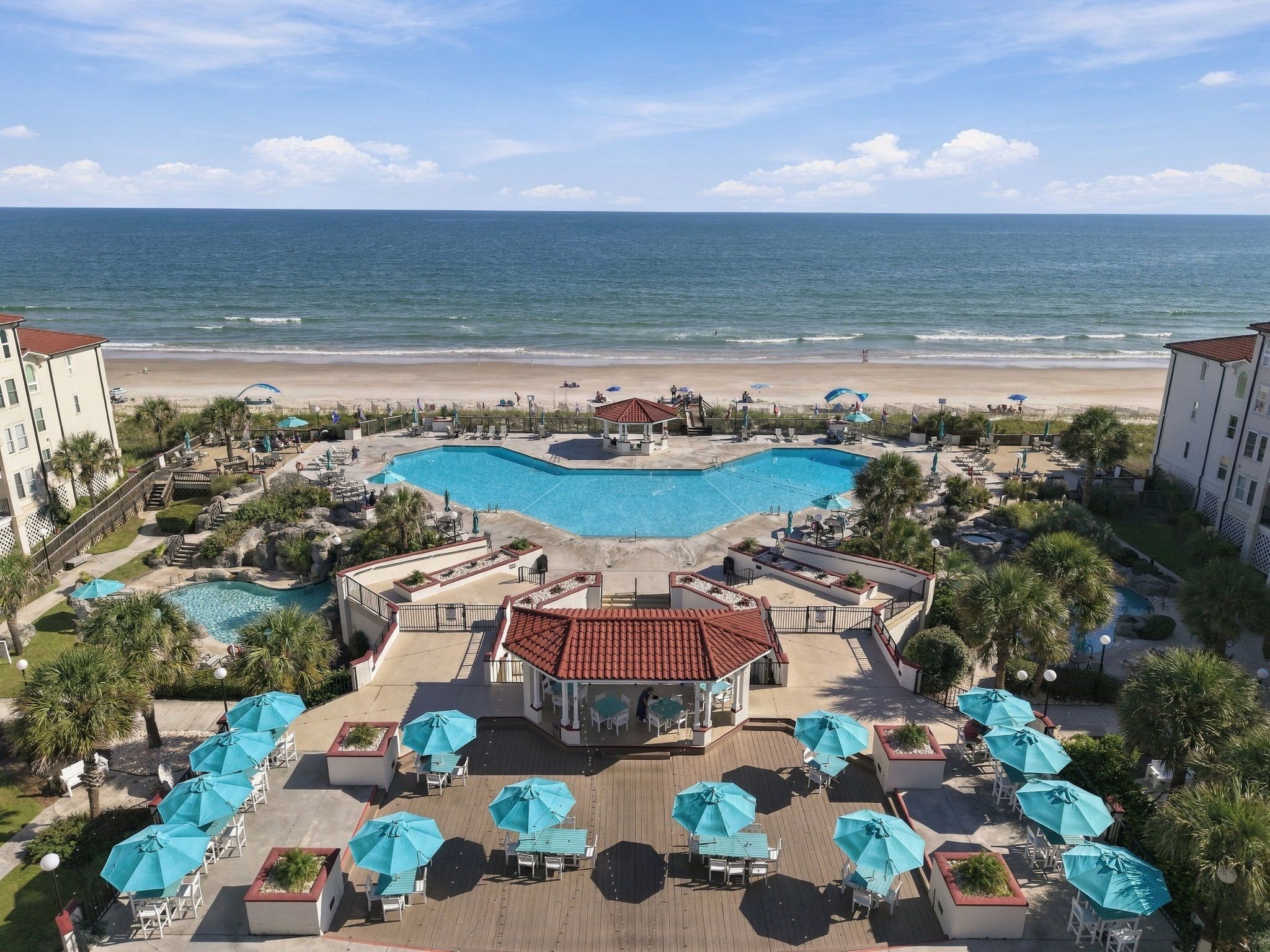 A resort with a central swimming pool, beach access, and outdoor seating areas.
