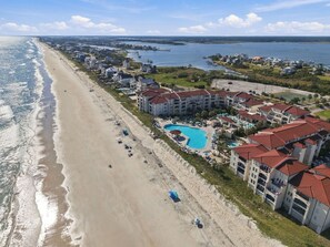 Aerial coastline view detailing the sandy beach, surf line, resort pool courtyard, and surrounding coastal community set between the ocean and sound. - Ocean Views, Pools Hot Tub & Beach @Villa Capriani (North Topsail Beach)