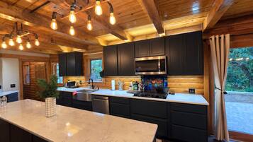 Una cocina moderna con una isla grande, armarios oscuros y un microondas de acero inoxidable.