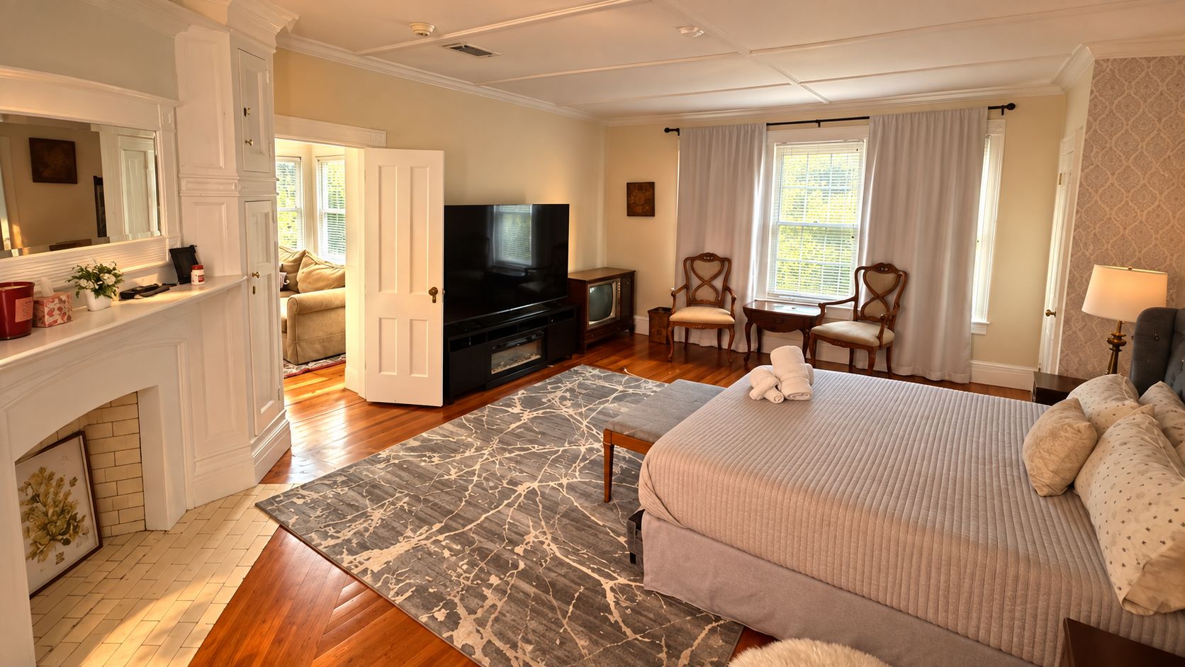 Una habitación de hotel con una cama, televisión, chimenea y zona de comedor.