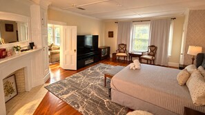 A hotel room with a bed, a television, a fireplace, and a dining area.