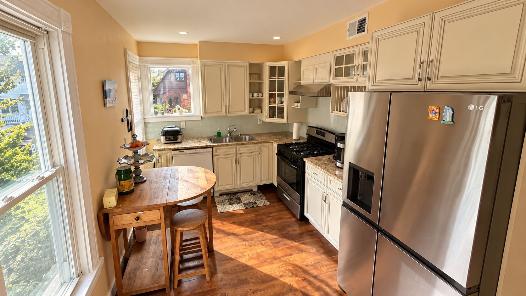 A kitchen with a wooden table, cabinets, a refrigerator, and a window with a view.