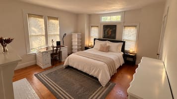A bedroom with a bed, bedside tables, a desk, and a chair.