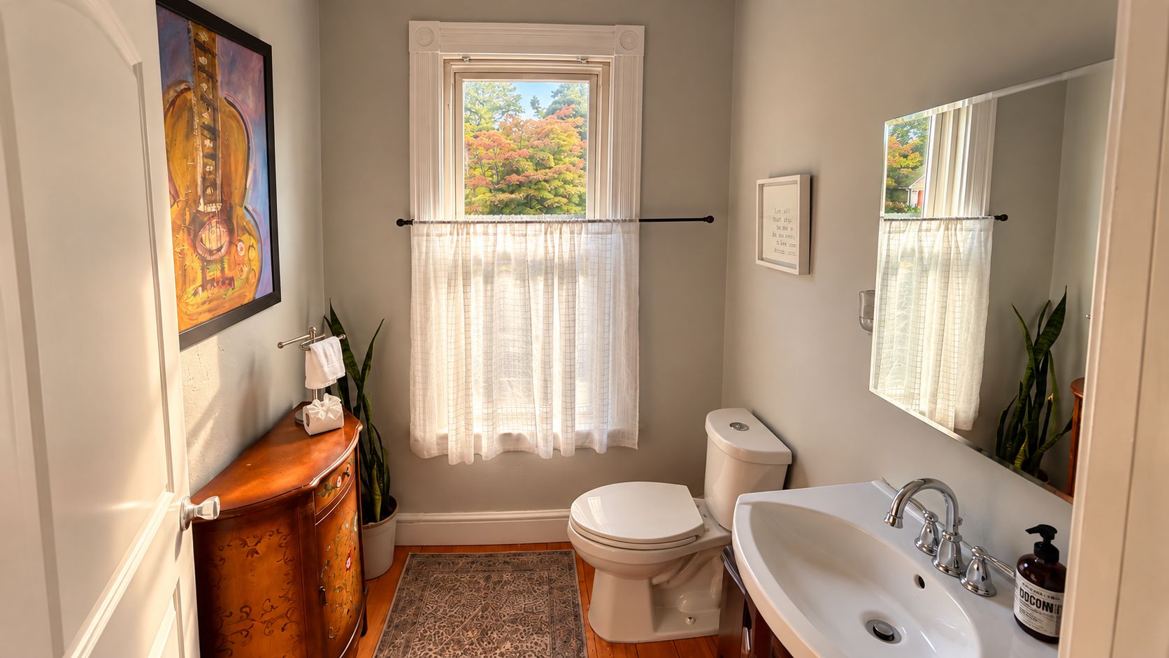 Un baño con inodoro, lavamanos y ventana con cortinas.