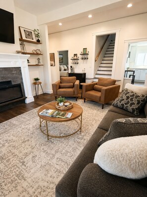 A living room with a fireplace, two brown leather sofas, a coffee table, and a patterned rug. - Cozy Cottage Near Downtown Bristol (Bristol)