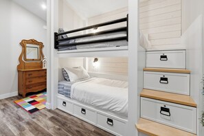 A bunk bed with storage drawers and a dresser in a bedroom. - The Heron's Rest • Walk to Little Beach | Family Cottage + Bunk Room (Ucluelet)