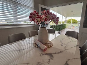 A dining table with a marble top, a woven placemat, and a vase with flowers. - Charming 3 Bdrm Parkside Qlder w Fabulous Deck. (Windsor)