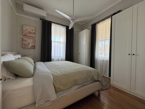 A bedroom with a bed, a ceiling fan, a wardrobe, and artwork on the wall. - Charming 3 Bdrm Parkside Qlder w Fabulous Deck. (Windsor)