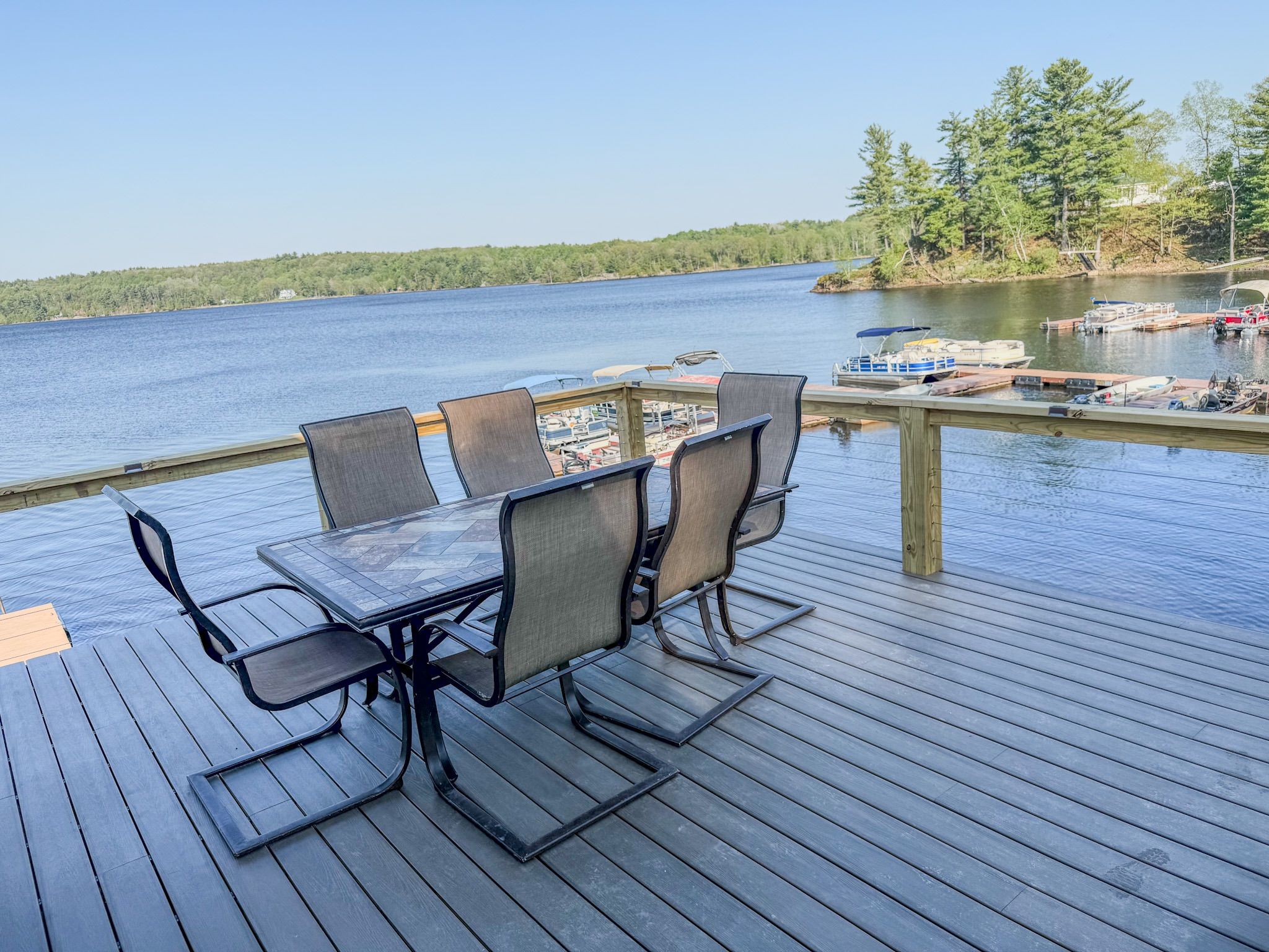 A wooden deck with a table and chairs overlooking a lake.