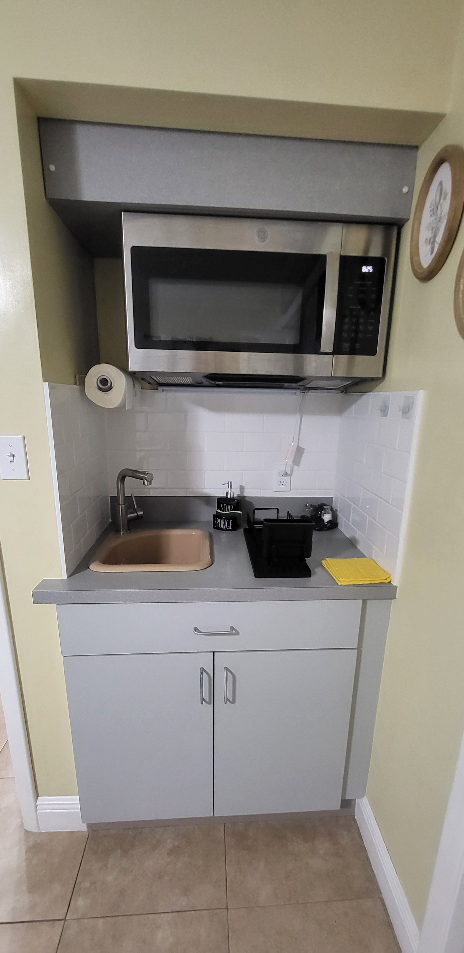 A compact kitchen with a built-in microwave, a sink, and a small countertop.