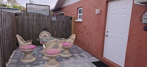A private property with a wooden fence, a glass table with chairs, and a white door.