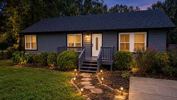 A two-story house with a front porch, a stone pathway leading to the entrance, and a well-maintained lawn.