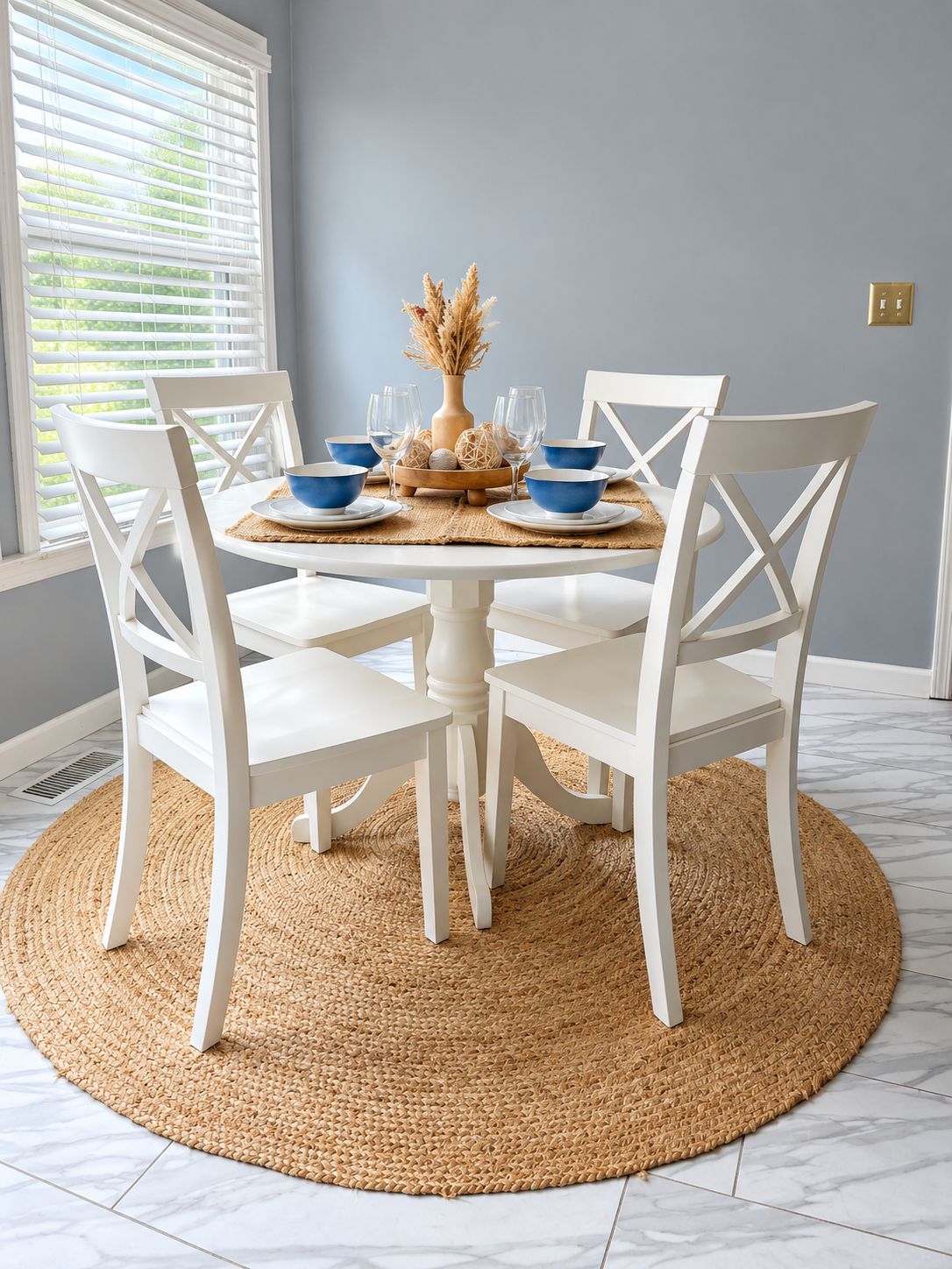 A dining area with a round table, white chairs, and a woven placemat.