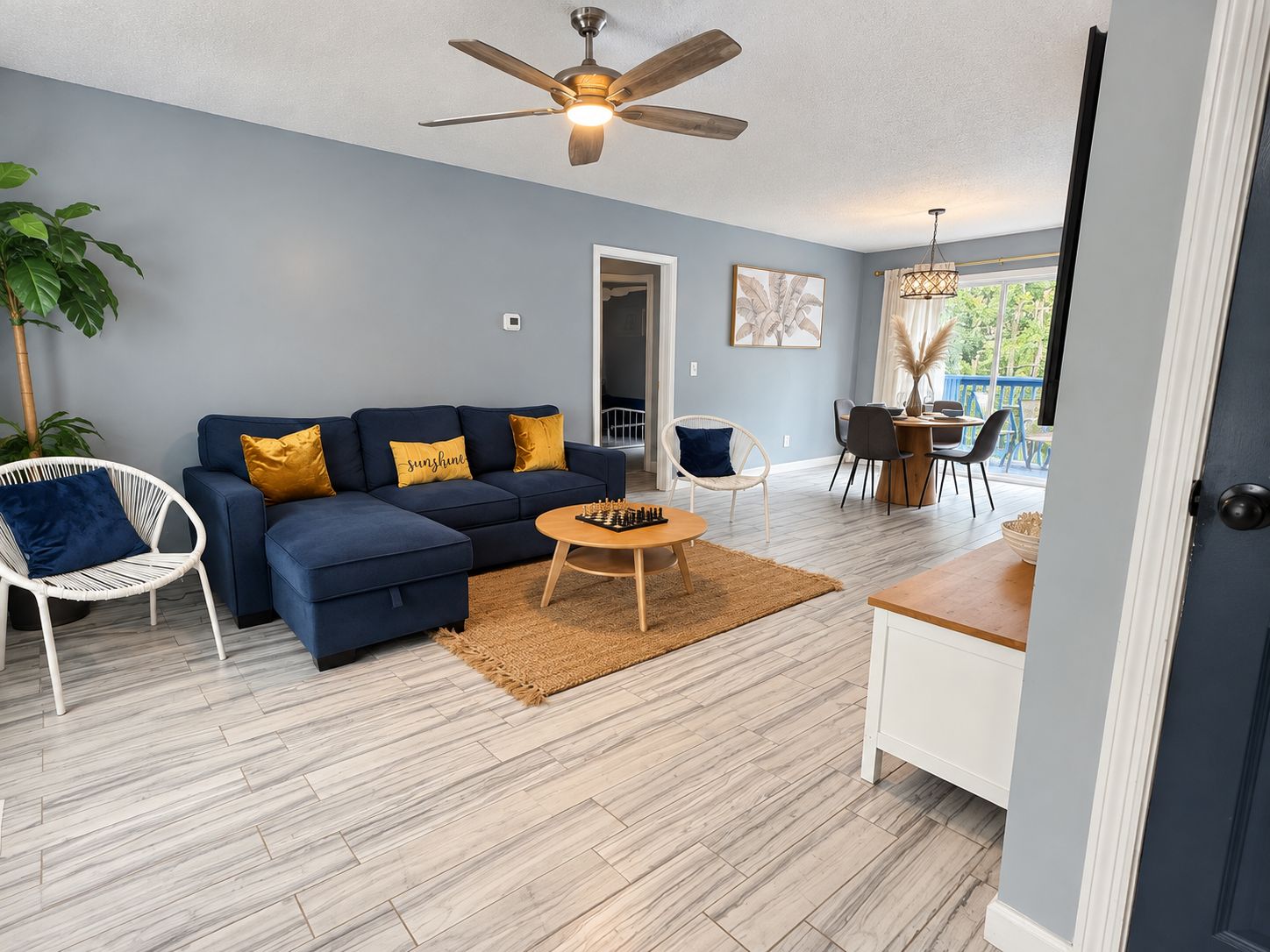 A modern living room with a blue sofa, a wooden coffee table, and a ceiling fan.