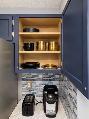 A kitchen with a built-in cabinet containing black and gold bowls, a toaster, and a Keurig coffee maker on the counter. - 5-bedroom Getaway w/ Private Pool, Arcade, Pool Table & More (Gastonia)