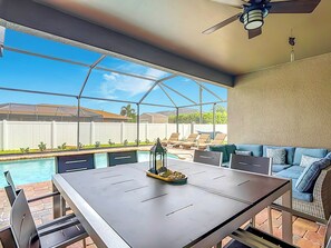 Eine überdachte Terrasse mit Pool, Gartenmöbeln und Blick auf den Garten.
