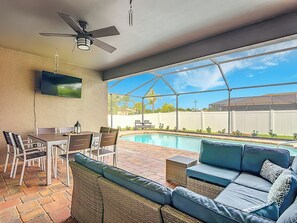 Eine überdachte Terrasse mit Pool, Sitzgelegenheit im Freien und Deckenventilator.