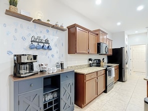 A modern kitchen with wooden cabinets, a coffee bar, and a coffee machine. - Coastal Vibes and Pool Days- Cape Coral-5BR/3BA/ Sleep 12 (Cape Coral)