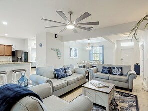 Una sala moderna con ventilador de techo, comedor con mesa y sillas, y cocina equipada.