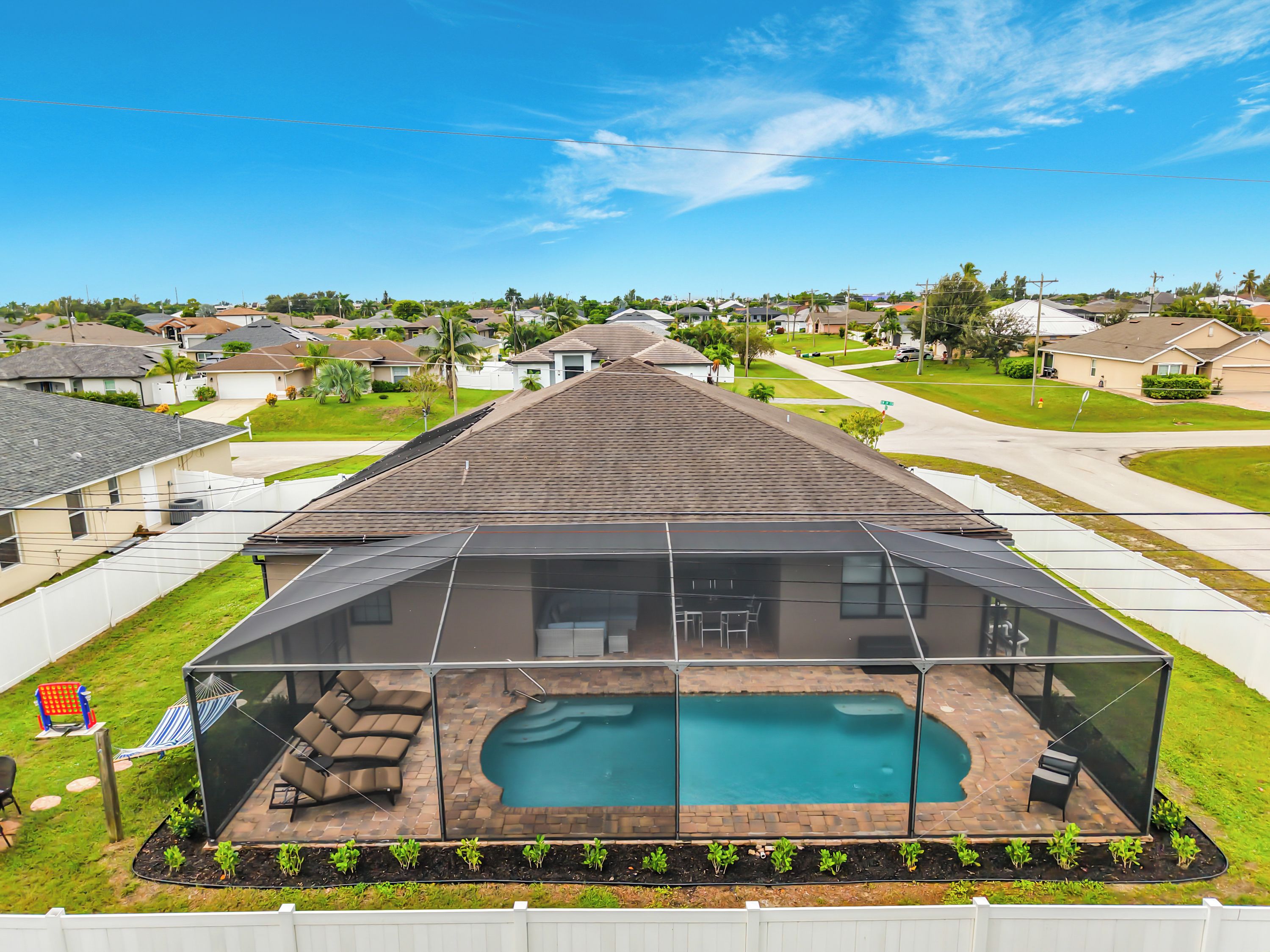 A residential property with a swimming pool, covered patio, and a view of the neighborhood.
