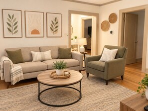 Ein Wohnzimmer mit Sofa, Sessel, Couchtisch und Wanddekoration.
