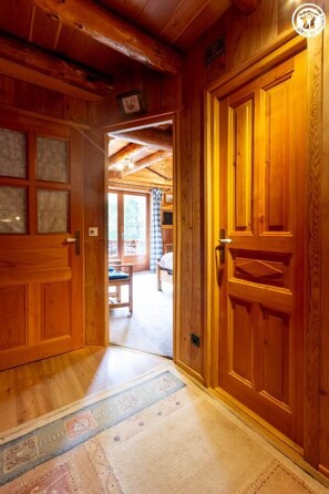 A wooden hallway with a carpet leading to a room with a bed and a window. - Les Abeillos - Le Marmotton (BONNEVAL SUR ARC)