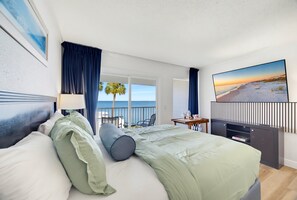 Ein Hotelzimmer mit Bett, Schreibtisch, Stuhl, Fernseher und einem Balkon mit Meerblick.