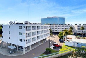 Ein mehrstöckiges Hotel mit weißer Fassade, Balkonen und einem Parkplatz.