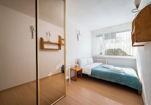 A bedroom with a bed, a nightstand, a mirror, and a window with a view. - Saska Kępa Homely Apartment (Warszawa)