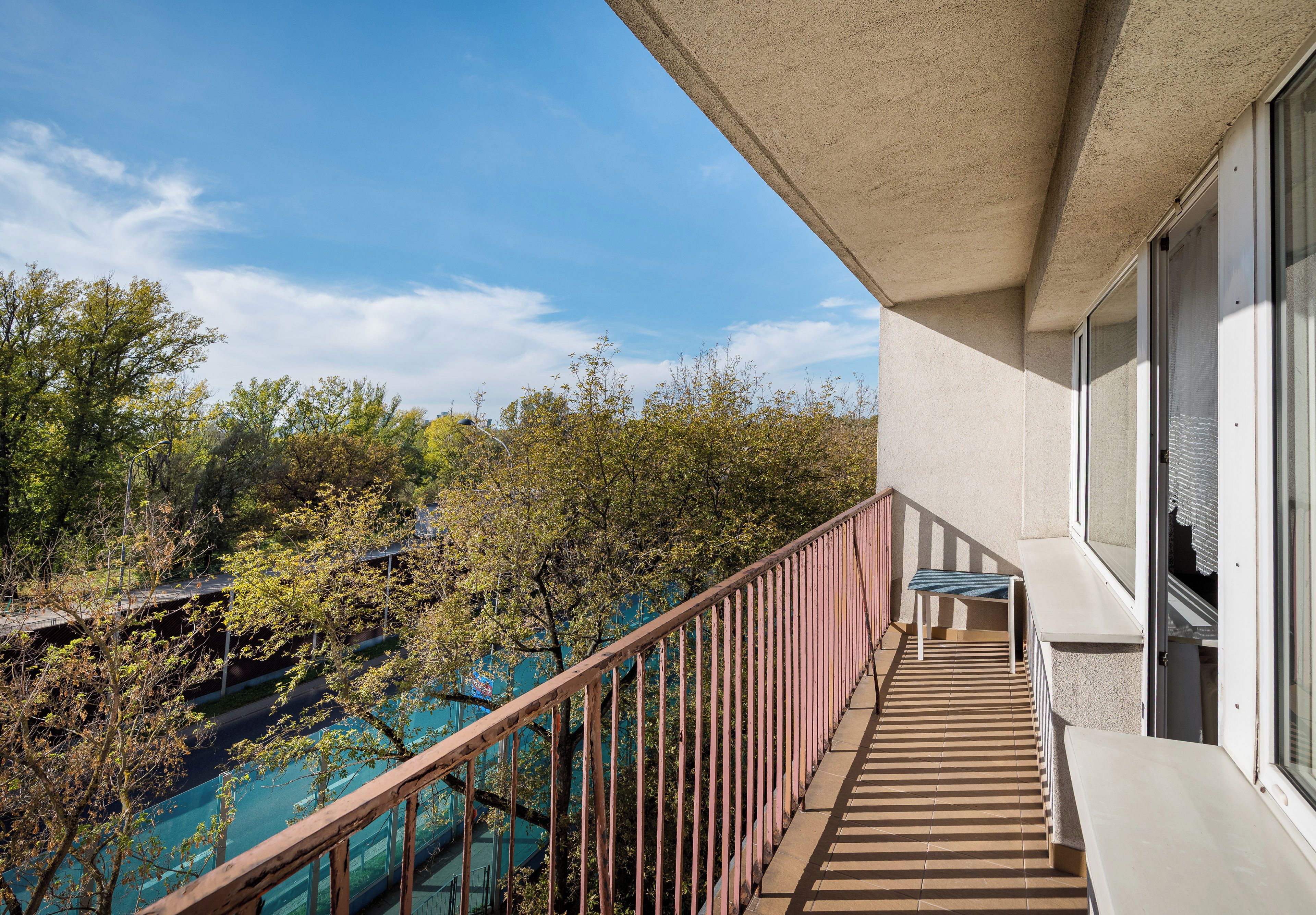 Un balcon donnant sur des arbres et un ciel dégagé.