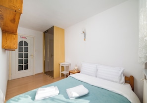 Ein Hotelzimmer mit einem Bett, einem Nachttisch, einer Wandlampe und einer Tür mit einem Fenster.