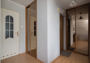 A hallway with wooden flooring, a white door with a glass panel, and a sliding door with a mirror. - Saska Kępa Homely Apartment (Warszawa)