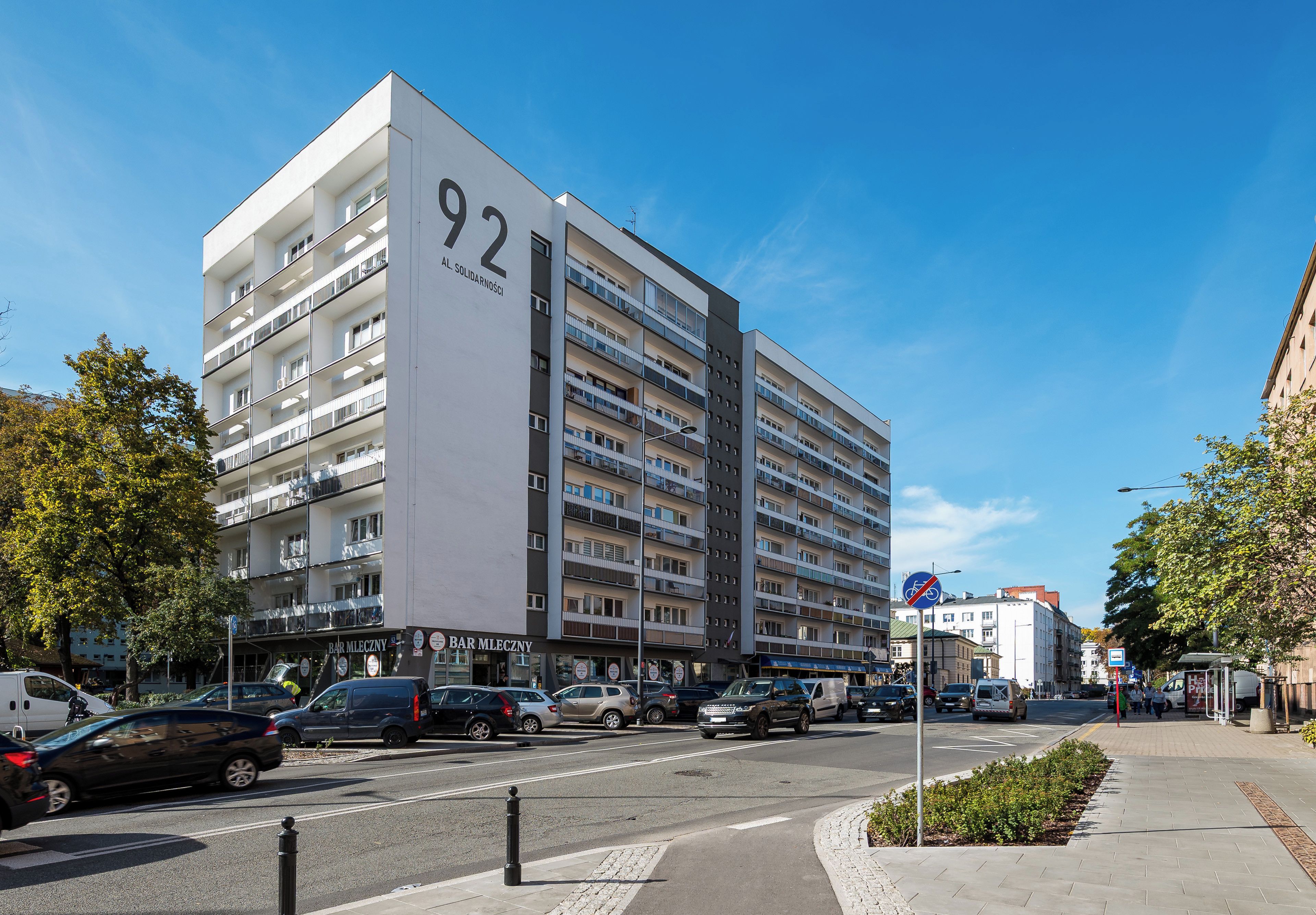 Un immeuble à plusieurs étages doté de balcons, avec une entrée bien visible et un ciel dégagé.