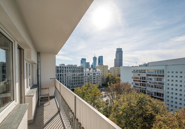 Ein Balkon mit Blick auf die Stadt, darunter moderne Gebäude und ein klarer Himmel.
