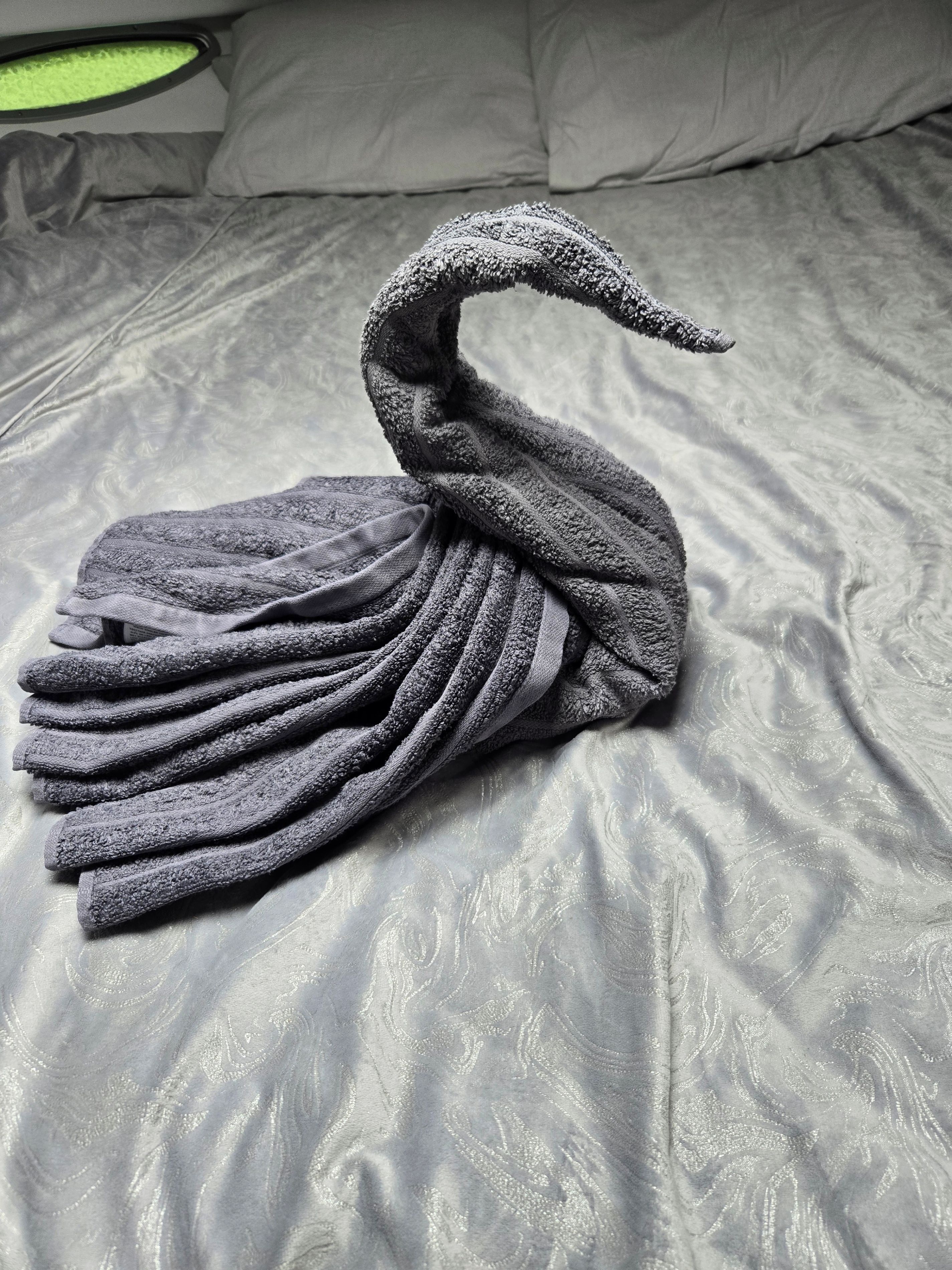 Un lit agrémenté d’une décoration en forme de cygne réalisée avec des serviettes.