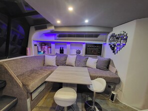 A modern lounge area with a sectional sofa, a small table, and two bar stools.