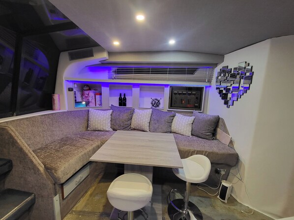A modern lounge area with a sectional sofa, a small table, and two bar stools.