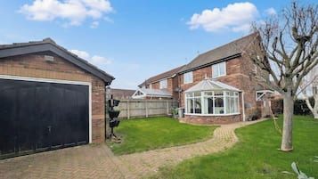 Il s’agit d’une propriété résidentielle comprenant une maison en briques, un garage, une véranda et une pelouse bien entretenue.