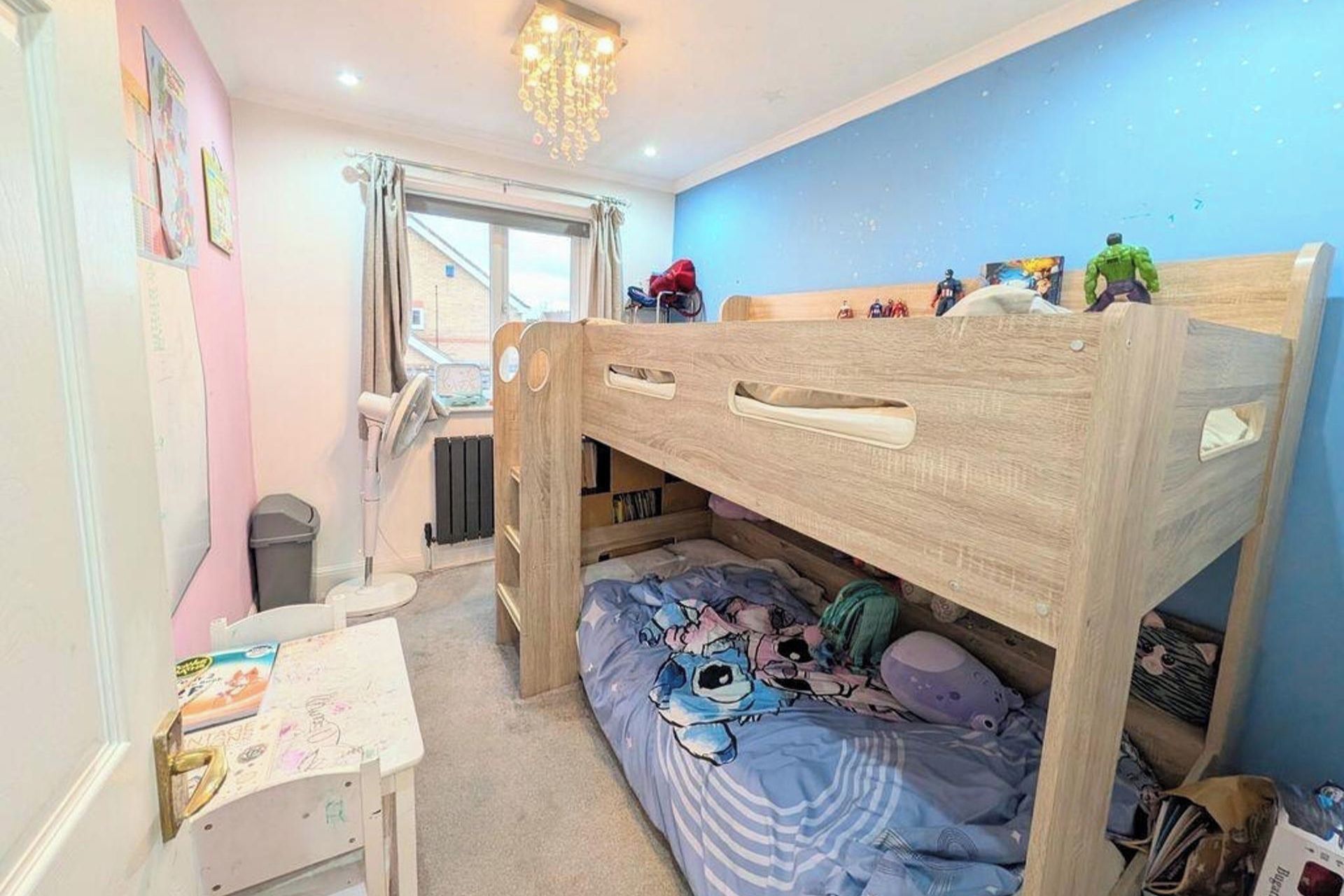 A child's bedroom with a bunk bed, a desk, and a window.